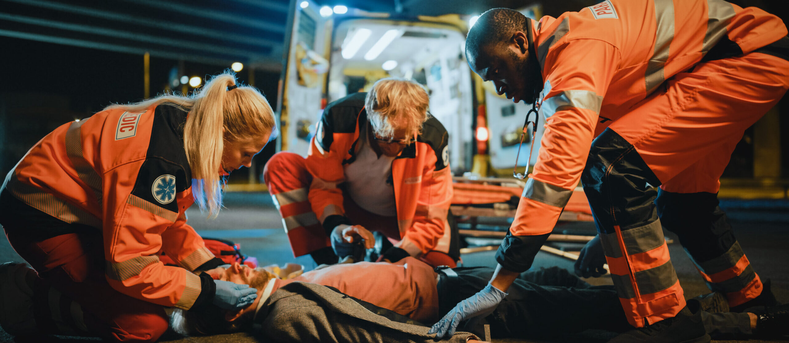 Three first responders attend to a patient laying on the ground